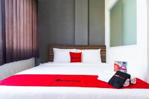 una camera da letto con un grande letto con una coperta rossa di RedDoorz near Seasons City Mall a Giacarta