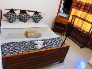 um quarto com uma cama com almofadas pretas e brancas em Polo Region Rest Inn em Haputale