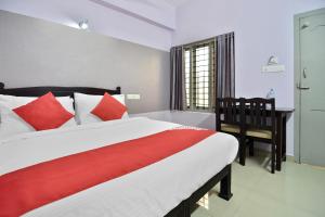a bedroom with a large bed with red pillows and a desk at Shanthi Residency in Pathanāmthitta