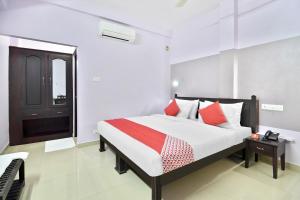 a bedroom with a bed with red and white pillows at Shanthi Residency in Pathanāmthitta