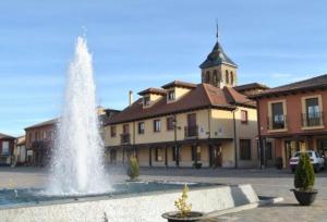 a fountain in front of a building with a church at MENCIA in Mansilla de las Mulas