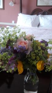 a vase filled with flowers on a table next to a bed at Gaultier Lodge in Woodstown