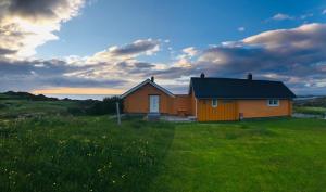 una pequeña casa en un campo con un campo verde en Midnight Sun Lodge Lofoten, en Bøstad