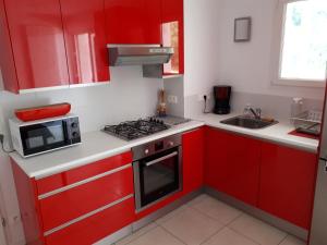 a red kitchen with a microwave and a stove at HENDAYE- T2 3*-Wifi-350m plage-terrasse-garage in Hendaye