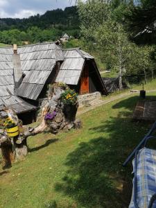 a house with a porch and a yard with flowers at Apartment Skulova Vodenica in Mokra Gora