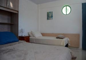een slaapkamer met 2 bedden en een klok aan de muur bij Quarto com entrada independente no centro de Petrópolis/RJ - Praça da Liberdade in Petrópolis