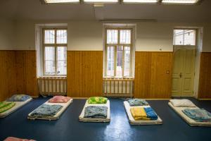 a room with nine beds on the floor with windows at Budget Hostel in Prague