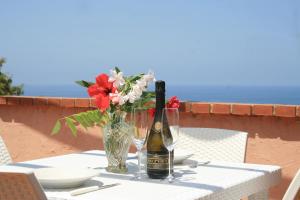 a bottle of wine and a vase of flowers on a table at Agroturistica Villa Mantineo in Capo Vaticano