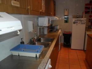 een keuken met een wastafel en een blauw dienblad op het aanrecht bij Sandras Backpackers in Thurso