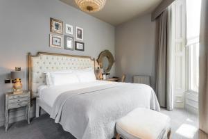 1 dormitorio con 1 cama blanca grande y espejo en Murrayfield Hotel en Edimburgo