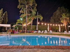 a swimming pool at night with tables and chairs at Hotel ausonia in Corigliano Calabro