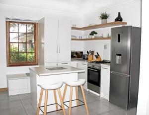 a kitchen with a stainless steel refrigerator and stools at Langbaai Beach Cottage in Hermanus