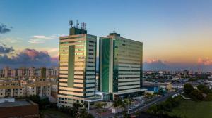 dois edifícios altos em uma cidade ao pôr do sol em Mais Hotel Aeroporto Salvador em Lauro de Freitas