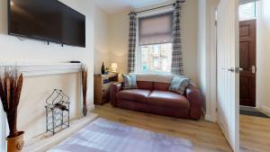 a living room with a leather couch and a television at StayZo Westminster Stylish House Accommodation in Bradford