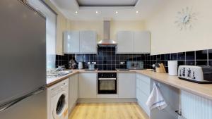 a kitchen with white appliances and black tiles at StayZo Westminster Stylish House Accommodation in Bradford