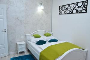 Una cama blanca con almohadas verdes en un dormitorio en KAYA STUDIO, en Sibiu