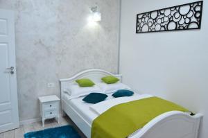 a white bed with green pillows in a bedroom at KAYA STUDIO in Sibiu