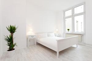 - une chambre blanche avec un lit blanc et une plante en pot dans l'établissement The Cloud, à Berlin