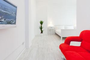 un salon avec une chaise rouge et une télé dans l'établissement The Cloud, à Berlin