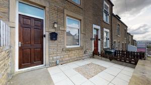 un edificio de ladrillo con una puerta y ventanas marrones en StayZo Westminster Stylish House Accommodation en Bradford