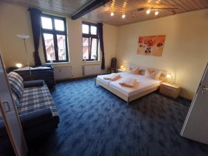 ein Schlafzimmer mit einem weißen Bett und einer Couch in der Unterkunft Ferienwohnungen Bergstrasse in Wernigerode