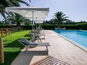 un gruppo di sedie e un ombrellone accanto alla piscina di Agriturismo Il Masseto a Venturina Terme