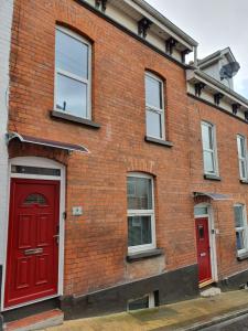 a brick building with red doors and windows at Harvey Apartments in Derry Londonderry