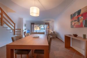 a dining room with a wooden table and chairs at Acolhedora Vivenda Geminada Praia D'el Rey in Casal da Lagoa Seca