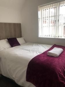 a bedroom with a white bed with a purple blanket at Safe Move - 23 Lancaster House in Leicester