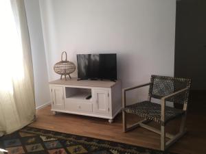 a tv sitting on top of a tv stand next to a chair at La casa accanto in Bari