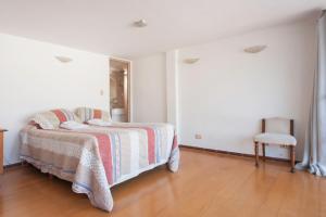 1 dormitorio blanco con 1 cama y 1 silla en Dúplex en Ático en Microcentro en Buenos Aires