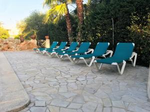 una fila di sedie blu sedute su un patio di Villa para 6 con piscina privada. a Ciutadella