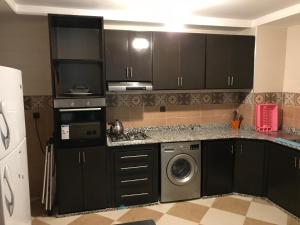 eine Küche mit schwarzen Schränken, einer Waschmaschine und einem Trockner in der Unterkunft Appartement Wynwood 3 in Oujda