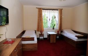 a bedroom with two beds and a tv and a window at Zajazd Ostoja in Stary Dzierzgoń