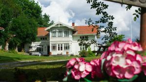 a white house with pink flowers in front of it at Fjøset på Knardal in Neset