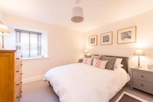 Un dormitorio con una gran cama blanca y una ventana en No.4 Ludbourne Hall en Sherborne