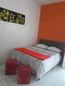 Bett in einem Zimmer mit zwei roten Stühlen in der Unterkunft Pousada Canto Verde Itanhaém in Itanhaém