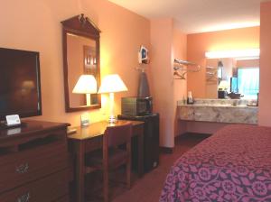 a hotel room with a bed and a desk with a television at America Best Value Inn Kosciusko in Kosciusko