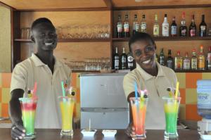 two men are standing behind a bar with drinks at Keur Papaye in Dinouar