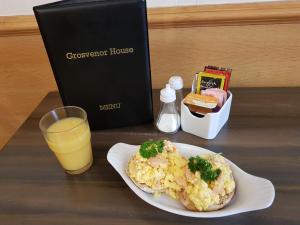 une table avec une assiette de nourriture et un verre de jus d'orange dans l'établissement Grosvenor House Hotel, à Torquay