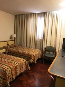 a hotel room with two beds and a chair at Hotel Cervantes in Mendoza