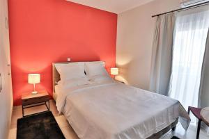 1 dormitorio con cama blanca y pared roja en V Luxury Apartment 2, en Ioannina