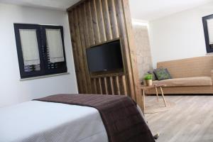 1 dormitorio con 1 cama, TV y sofá en A Casinha da Padaria, Soajo, en Soajo