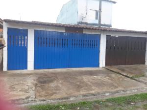 a garage with blue doors and a building at Aconchegante casa para temporada in Mongaguá