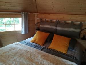 a bedroom with a bed with two orange pillows at Camping Loisirs Des Groux in Mousseaux-sur-Seine