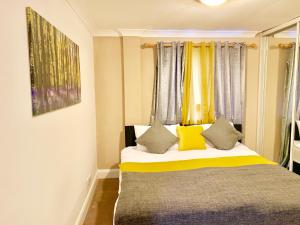 ein Schlafzimmer mit einem Bett mit gelben und grauen Kissen in der Unterkunft 2 Bedrooms Modern Central London Apartment, Full Kitchen, 5 minutes Tube Station in London