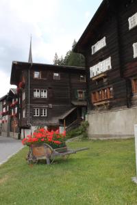 ein Holzgebäude mit einem Haufen Blumen im Gras in der Unterkunft Jentsch Haus in Niederwald