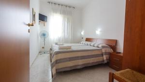 a bedroom with a bed and a window with a fan at Casa Vacanze L'Orizzonte in Valderice