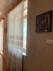 - une fenêtre avec un rideau blanc dans la chambre dans l'établissement Tamila Guest House, à Kazbegi