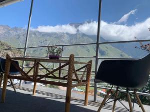 a table and chair on a balcony with a view of mountains at Tamila Guest House in Stepantsminda